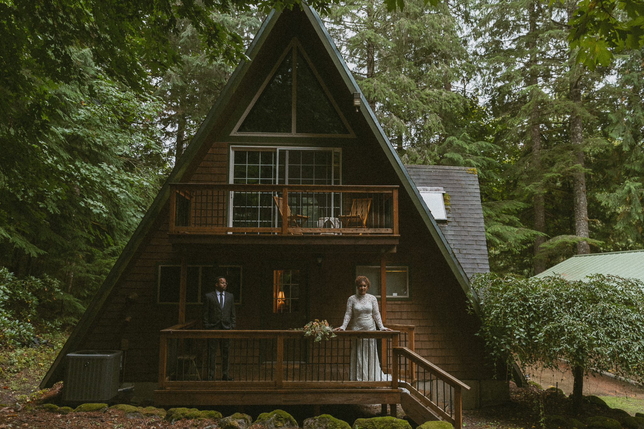 bride and groom look out from balcony after saying their vows in cozy a-frame cabin