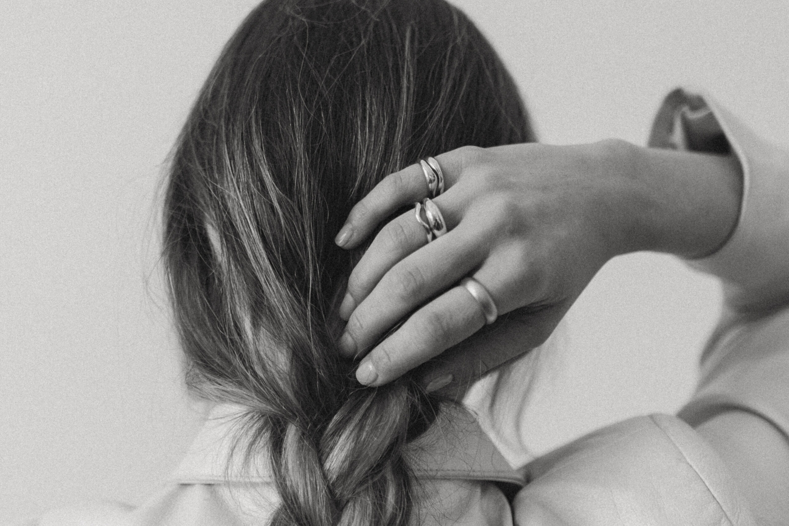 woman wears handmade rings while messing with braided hair