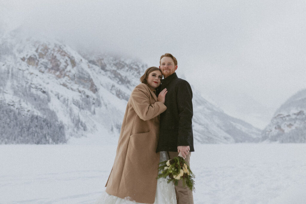 Bride and groom hugging each other and being cozy during their Alberta winter elopement