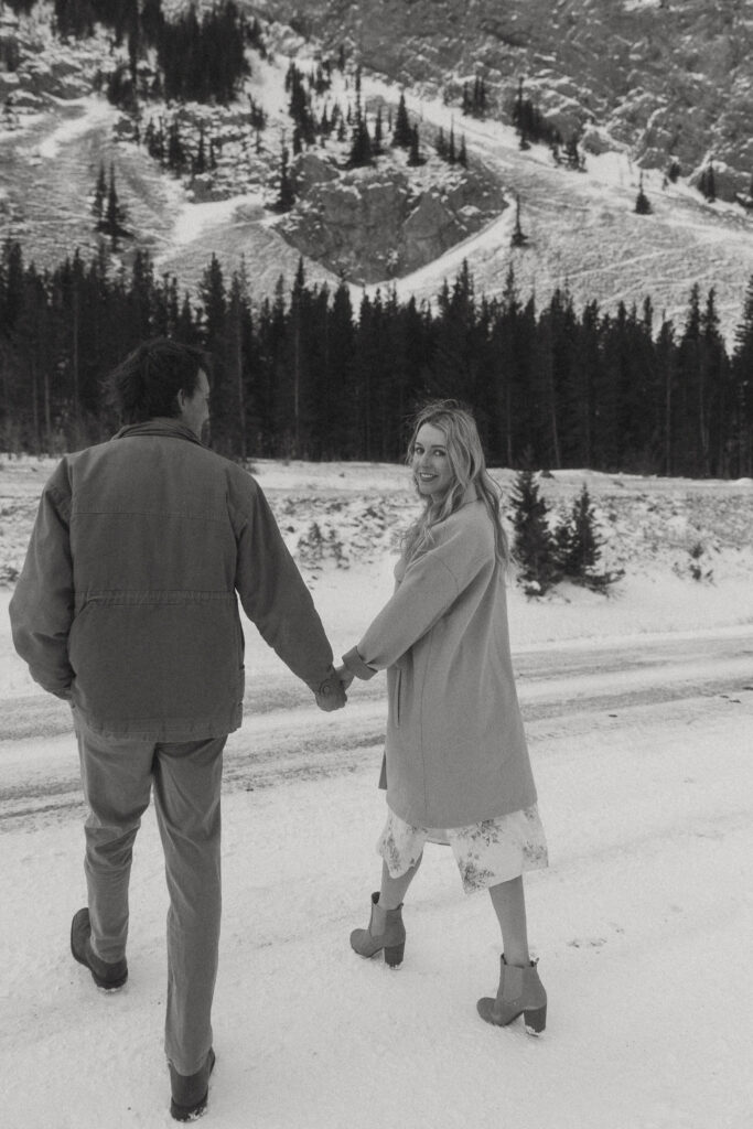 young couple holds hands while talking with a mountain in the background