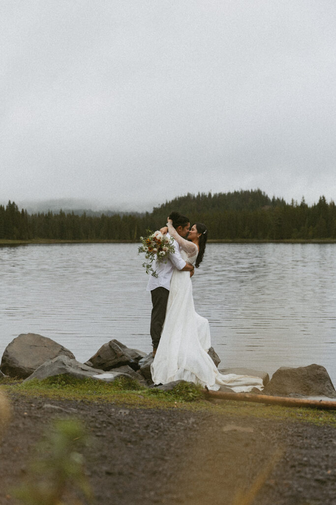 romantic bride and groom by a lake during their adventure elopement in Alberta