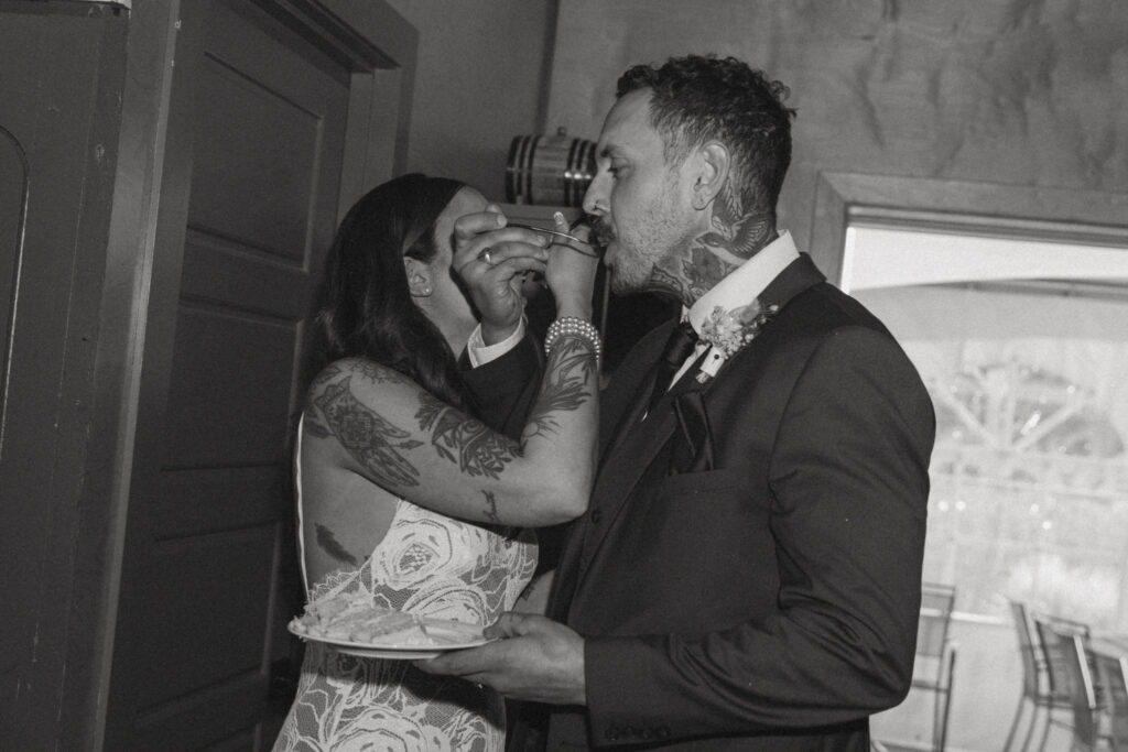 bride and groom eating cake at wedding reception at fernie distillers