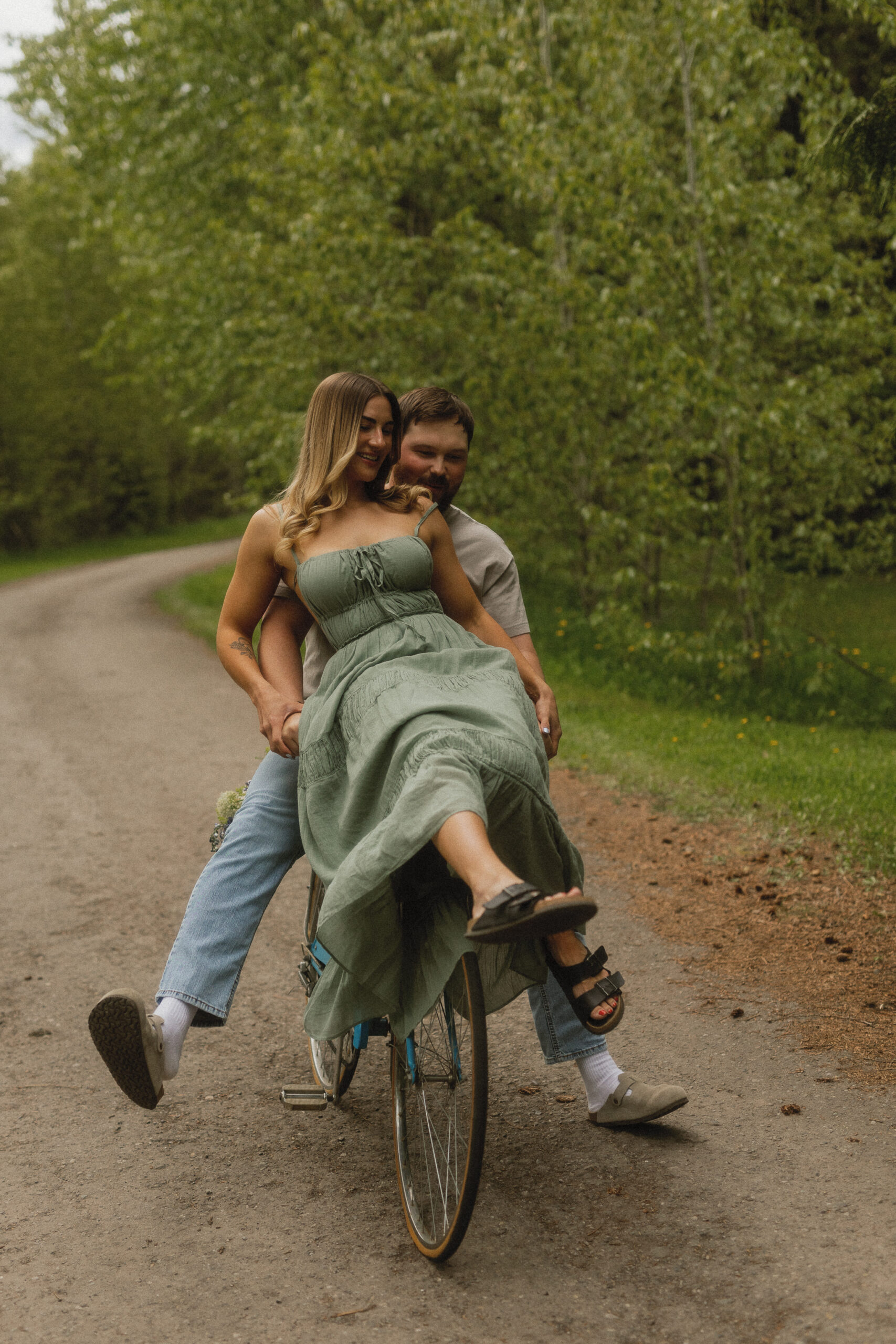 young couple ride vintage bike down dirt road in fernie, bc