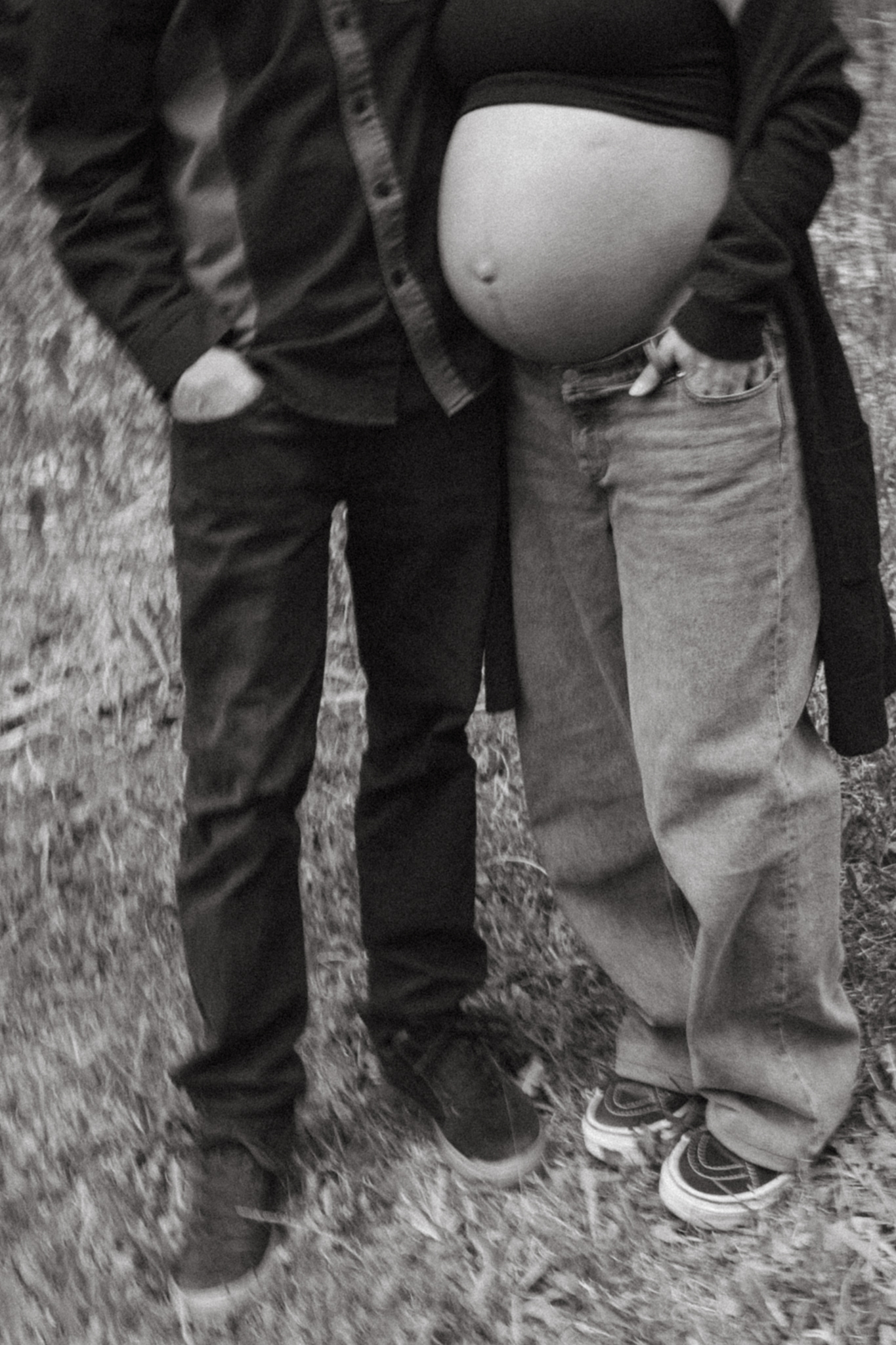 Ang and caleb stand together under the tall trees in Fernie during their maternity session