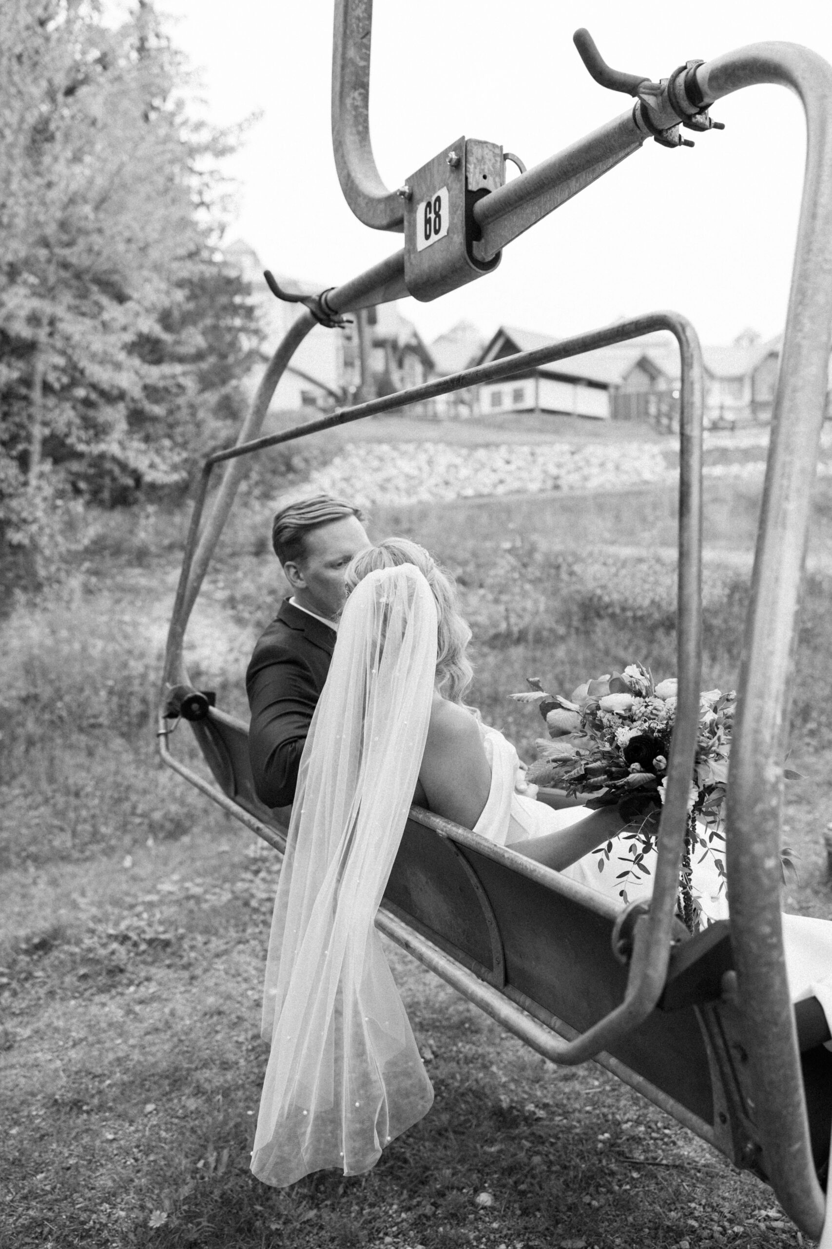 bride and groom sit on fernie ski hill chair lift at their fernie wedding